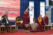 Поднявшись на сцену, Его Святейшество Далай-лама приветствует слушателей перед началом лекции в Тумкурском университете. Тумкур, штат Карнатака, Индия. 26 декабря 2017 г. Фото: Тензин Чойджор.
